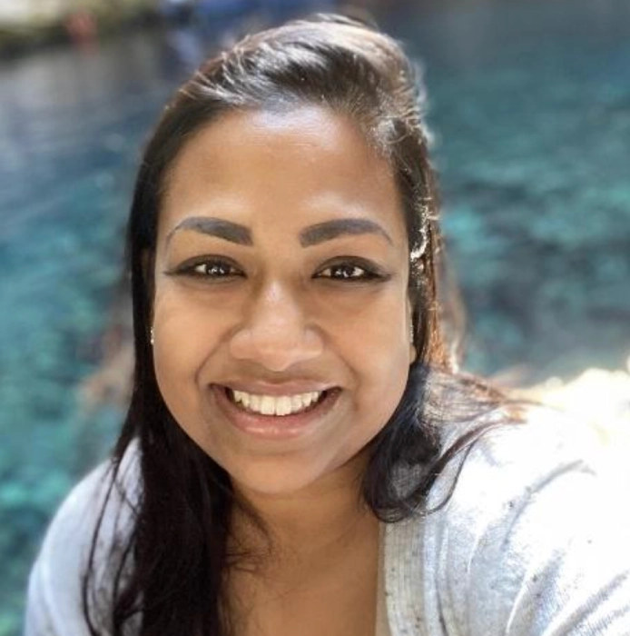A woman with long dark hair smiles at the camera with clear blue water in the background, perfect for the Central Florida Animal Reserve media kit.